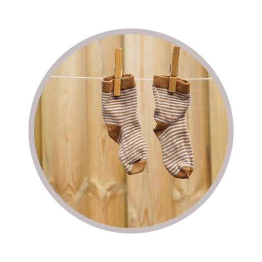 pair of stripped socks on laundry line in front of fence