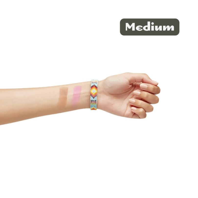A hand with three swatches of Cheekbone Beauty Blush & Bronzer Duo in different shades on the inner forearm, wearing a colorful bracelet. The word Medium appears in a gray box at the top right.