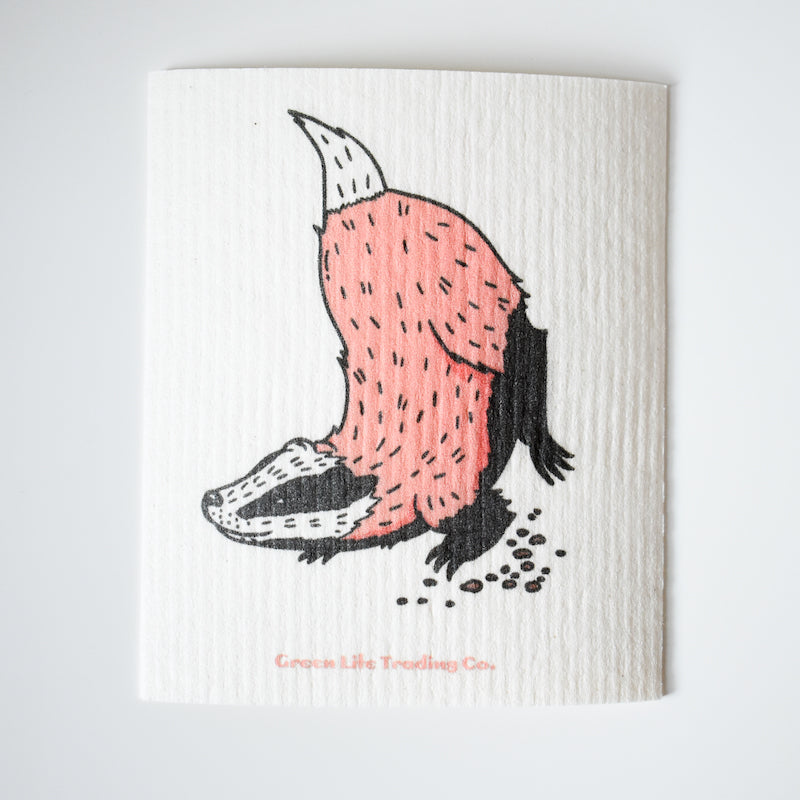 The Potluck Press Swedish Dishcloth features a washable, super absorbent design with a badger digging—pink and black fur, head down and tail up—illustrated on a white background.