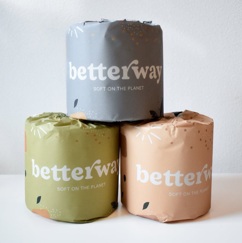 Three rolls of Betterway Bamboo Toilet Paper, each wrapped in gray, green, and peach paper, are stacked pyramid-style against a white background. Soft on the Planet is visible on this eco-friendly Betterway product.