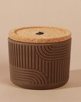 Brown textured container with a cork lid on a beige background