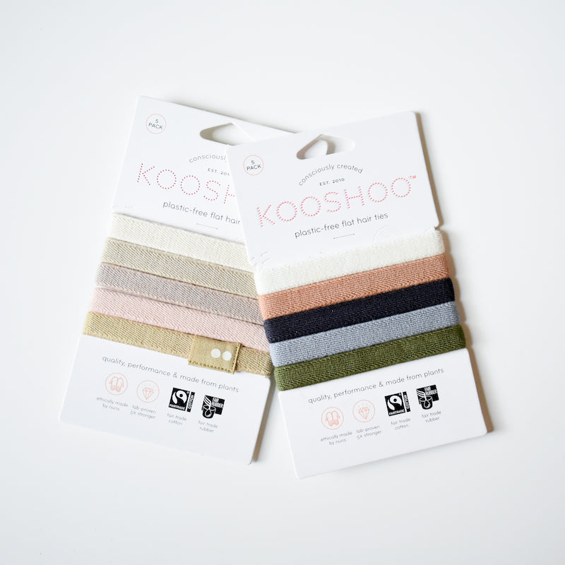 Two packs of KooShoo Biodegradable Hair Ties, each with five elastic bands in assorted neutral colors, presented on white eco-friendly packaging.