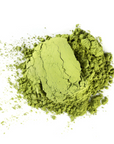 A mound of Mountain Rose Herbs Matcha Powder sits on a white surface, with fine green powder dusted around the main pile.