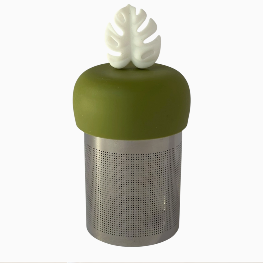 The Teany Tiny Kitchen Floating Tea Infuser features a green silicone top and white leaf handle, standing upright for easy tea steeping—an innovative design perfect for any tea lover.
