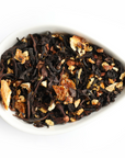 A teardrop-shaped white bowl holds Mountain Rose Herbs’ Orange Spice Tea—loose leaf black tea blended with dried orange peel and spices—displayed against a white background.