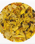 A circular pile of Glow Herbal Tea by Loose Leaf Tea Co. features yellow flower petals, light fruit pieces, and small dark bits, all displayed on a white background.