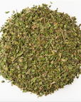 A circular pile of dried, chopped green herbs on a white background resembles the classic Peppermint Herbal Tea leaves from Loose Leaf Tea Co.