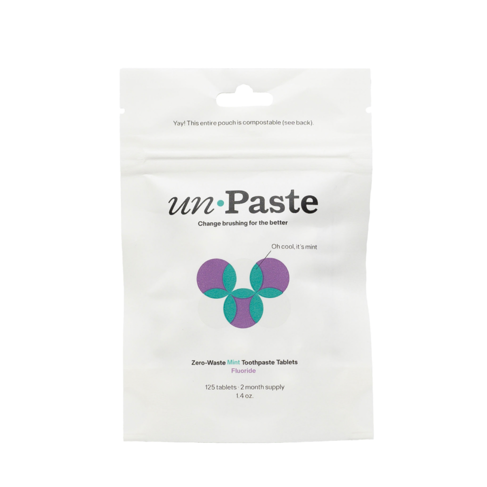 Unpaste Fluoride Tooth Tabs come in a white, compostable pouch with green and purple geometric design. This vegan, zero-waste mint formula provides 125 tablets—a two-month supply—from Unpaste.