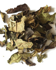 Loose, dried White Peony Tea leaves from Mountain Rose Herbs in green and brown hues, scattered on a white surface.