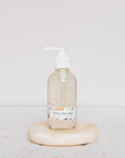 A clear pump bottle labeled Carina Organics Hair Styling Gel rests on a round, light stone with a white background. This alcohol-free gel defines curls while keeping a natural look.