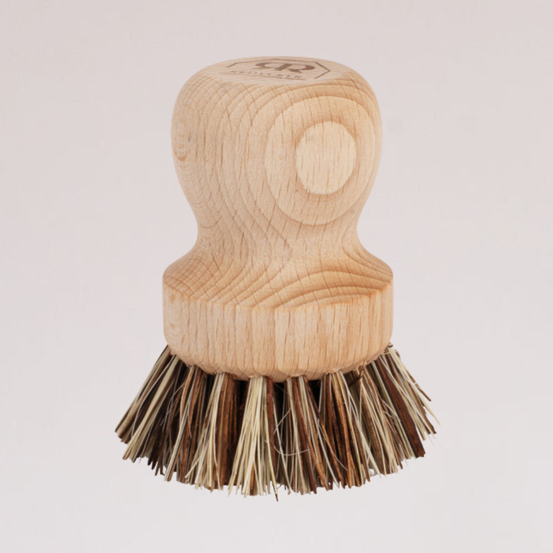 The Zefiro Pot Brush features stiff union fiber bristles in a circular pattern and a wooden handle, shown upright against a plain light background.