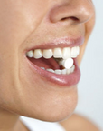 A close-up of a person smiling with their mouth open, about to take an Unpaste Fluoride-Free Tooth Tab from Unpaste on their tongue—an ideal travel-friendly toothpaste alternative.