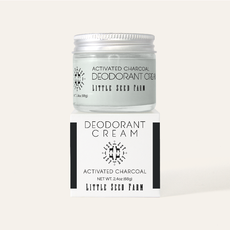 A refillable Jar of Activated Charcoal deodorant on top of its white and black box. 