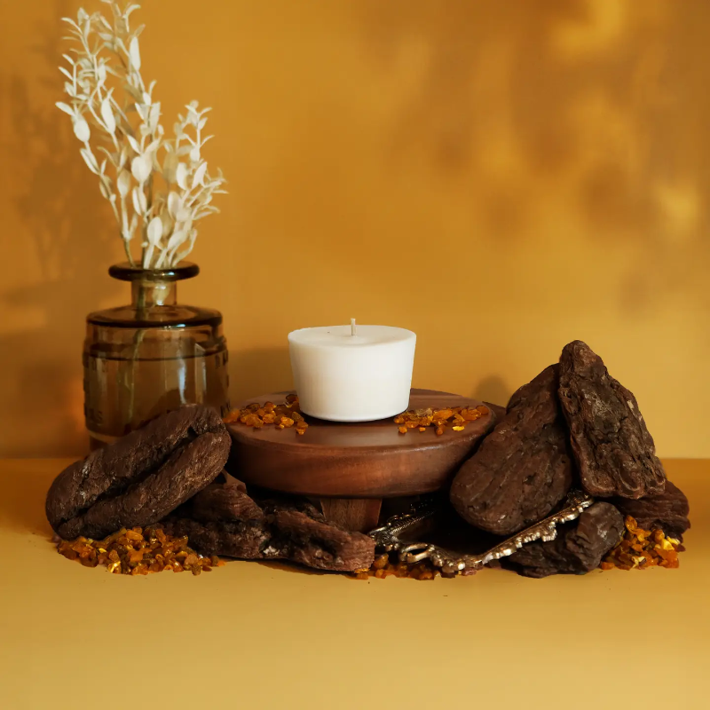 The Arbor Made Candle Refill in the scent Golden Hour. The candle refill is unpackaged in the center surrounded by stones and resin on a golden background. 