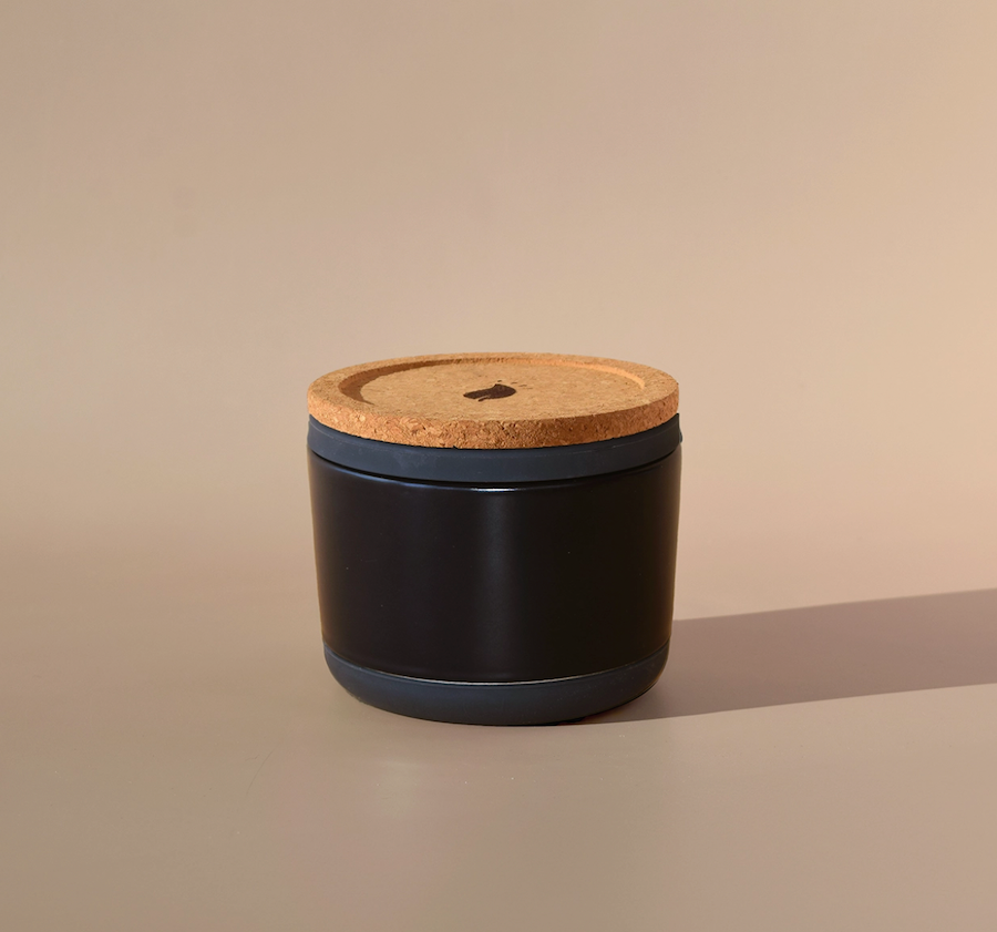 black ceramic candle jar with cork lid on tan backdrop