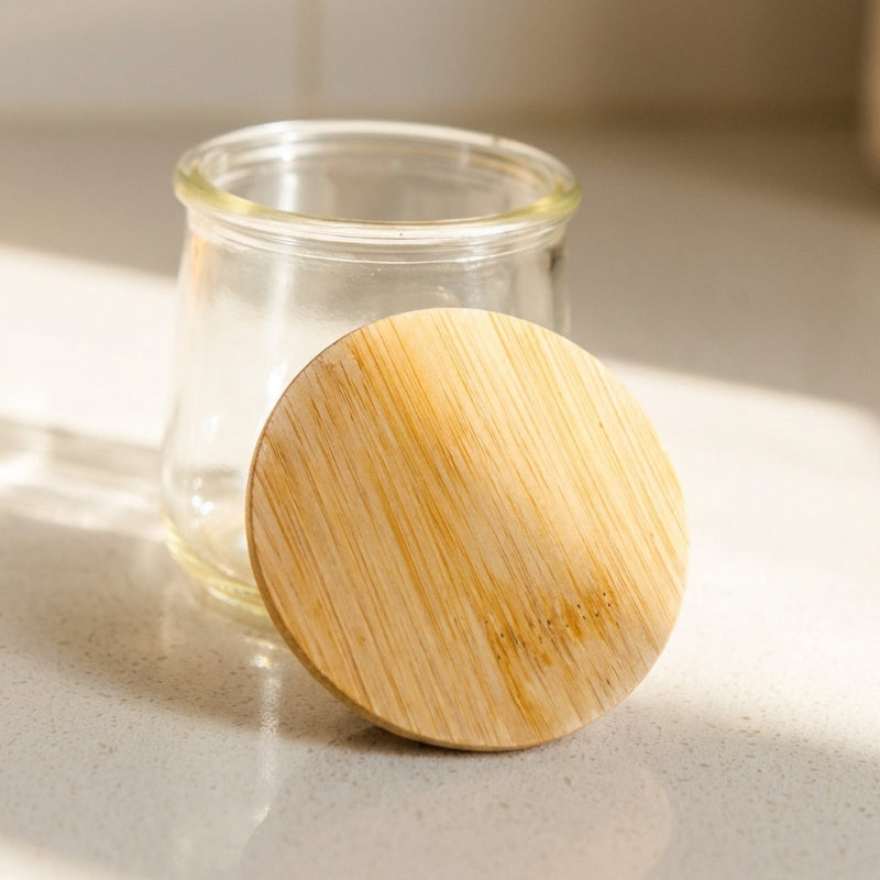A small Oui yogurt jar with a bamboo lid resting on it, ready to be reused!