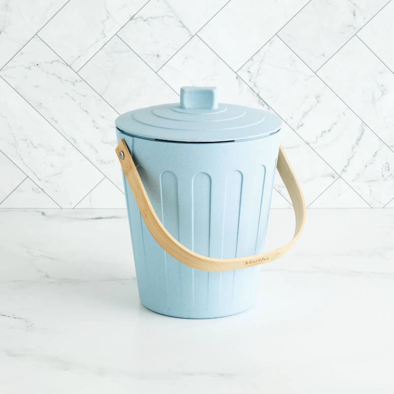 Light blue small compost bin on a marble counter.