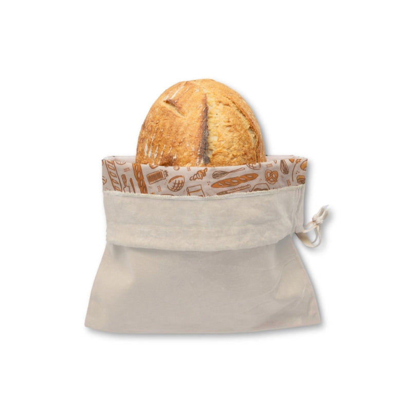 A beige bread bag with a drawstring closure, shown holding a round loaf of bread on a plain white background. The opening is folded down showing its bee's wax lining printed with baked goods illustrations. 