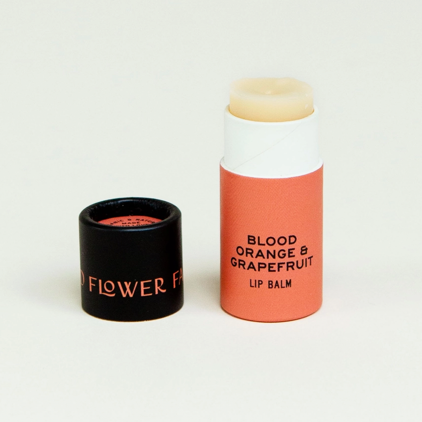 paper tube of natural lip balm orange and black packaging on white backdrop