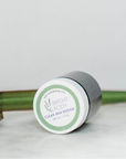 The Bright body Clear Skin Potion  jar on its side showing the lid and the floral logo on it. 