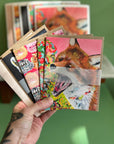 A hand hold a fan of greeting cards with high quality prints of oil paintings by  local Madison artist Natalie Jo Wright. 