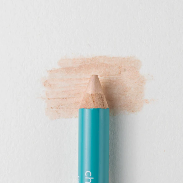 A close up on the Cheekbone Beauty vegan mini eyeshadow pencil and a swatch behind the pencil tip. This is the shade honey calcite, a champagne with light shimmer. 