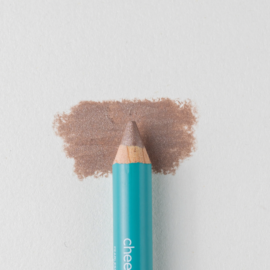 A close up on the Cheekbone Beauty vegan mini eyeshadow pencil and a swatch behind the pencil tip. This is the shade  brown topaz, a taupe brown with a light shimmer. 