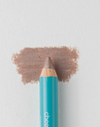 A close up on the Cheekbone Beauty vegan mini eyeshadow pencil and a swatch behind the pencil tip. This is the shade  brown topaz, a taupe brown with a light shimmer. 