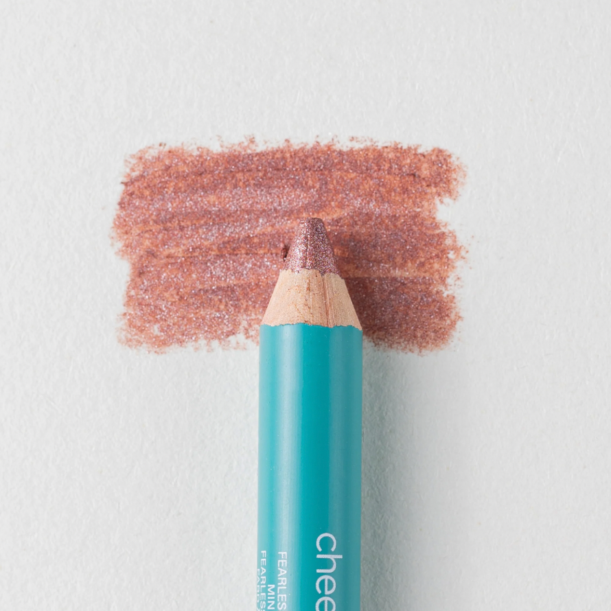 A close up on the Cheekbone Beauty vegan mini eyeshadow pencil and a swatch behind the pencil tip. This is the shade Rose Quartz, a warm pink with light shimmer. 