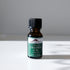 A small brown glass bottle with a black cap labeled Mountain Rose Herbs Cinnamon Leaf Essential Oil, 1/2 fl. oz. (15 mL), sits on a white surface for aromatherapy, its shadow cast to the right.