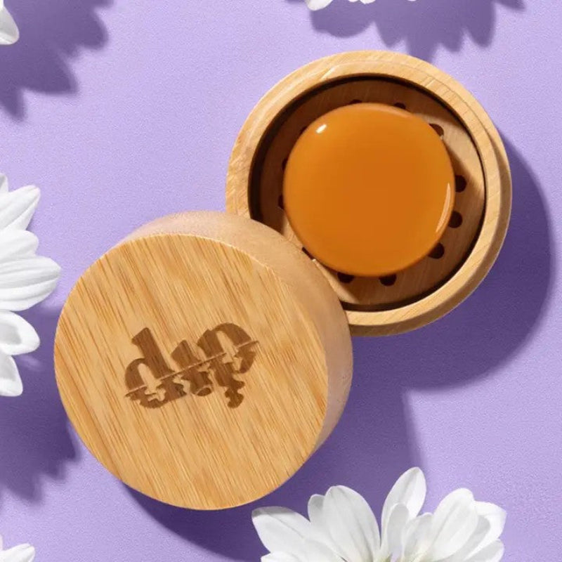 A Mini Dip travel case open to show a conditioner bar inside on a purple background 