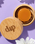 A Mini Dip travel case open to show a conditioner bar inside on a purple background 