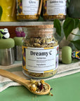 A refillable jar of dreamy c tea. The jar has a cork lid and an attachable bamboo spoon. 