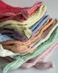 A stack of colorful hemp exfoliating washcloths with a handy drying loop on a white background.