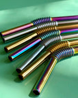 An array of reusable enable metal straws in multiple finishes on a green background. 