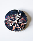 Round woven item with tree design and twine on a white background