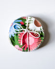 Round, colorful fabric product with a floral pattern on a white background