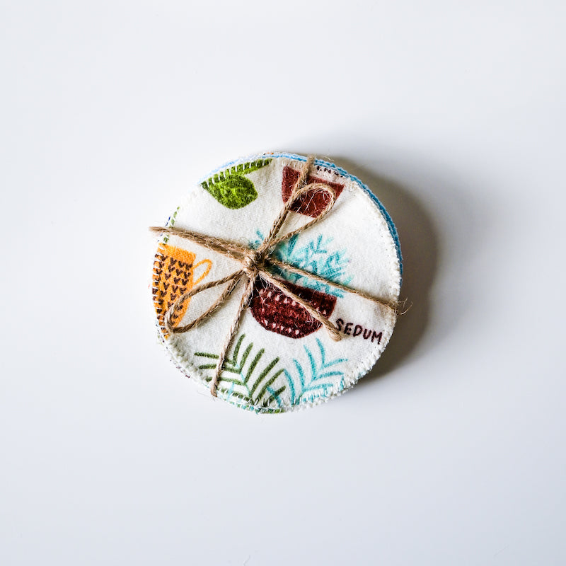 Round fabric coaster with plant-themed design and twine on a white background