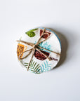 Round fabric coaster with plant-themed design and twine on a white background