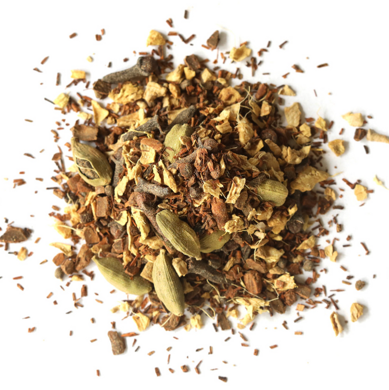 A pile of Mountain Rose Herbs Firefly Chai Tea blend, with visible dried cardamom pods, cloves, ginger pieces, and cinnamon, scattered on a white background.