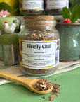 A refillable jar of firefly chai tea. The jar has a cork lid and an attachable bamboo spoon. The spoon is in front of the jar with tea in it. 