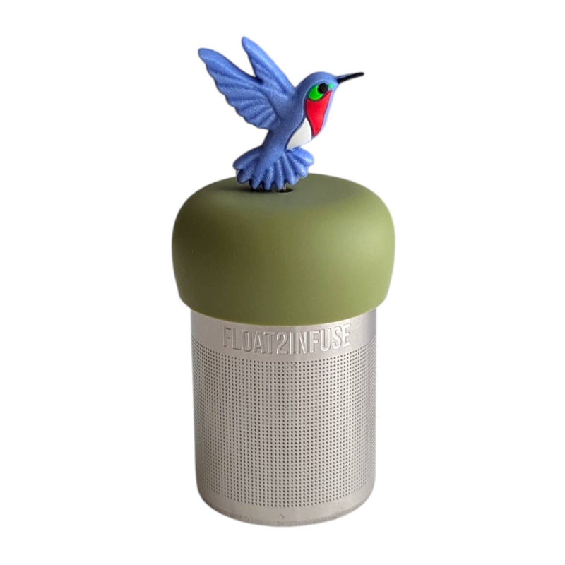 A Stainless steel and silicone floating tea infuser. The top silicone part is green with a blue red and green hummingbird  charm on top of it.