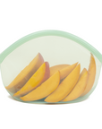 A Green Transparent reusable silicone bag with sliced mango in it on a white background.
