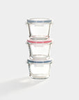 Three borosilicate glass containers in light blue, red, and dark blue stacked on top of each other on a white background. 