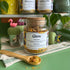 A refillable jar of glow tea. The jar has a cork lid and an attachable bamboo spoon. 