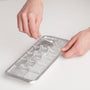 Person using a metal ice cube tray on a light gray background