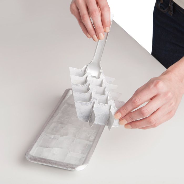 Person removing ice cube trey divider on a light gray surface