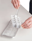 Person removing ice cube trey divider on a light gray surface