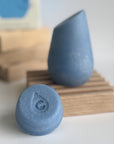 The blue hibar mini conditioner in Moisturizer sample leaning on a soap dish in front of the full size conditioner. 