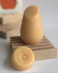 The orange hibar mini conditioner in volumizer sample leaning on a soap dish in front of the full size conditioner. 